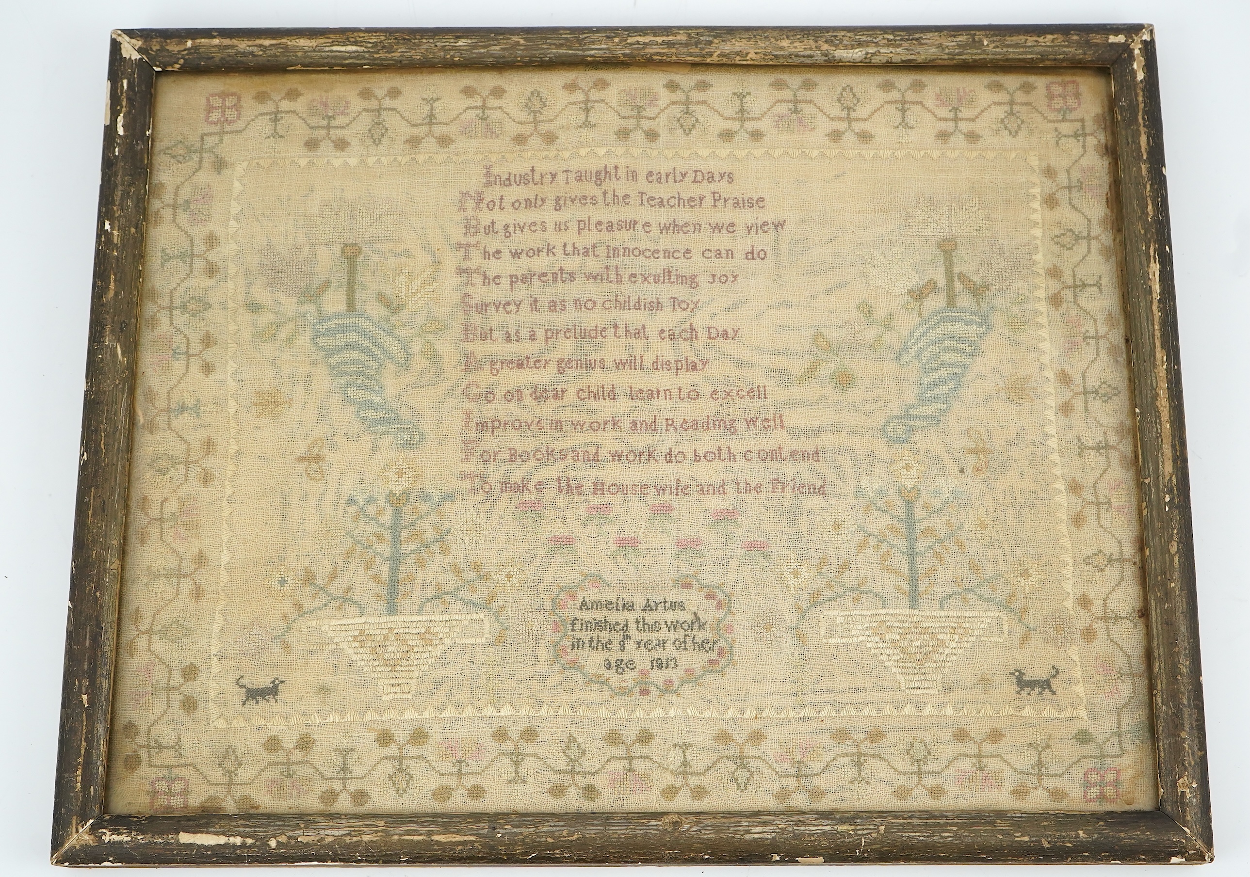 A gilt framed finely worked Regency gauze sampler, by Amelia Artus, aged 8 years, dated 1813, worked on fine gauze with coloured silk threads, with a large central panel having a long verse, two motifs of cornucopia, pot